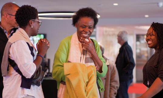 A group of people chat happily in a cinema foyer. 