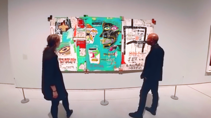 Photo of two people looking at Basquiat painting