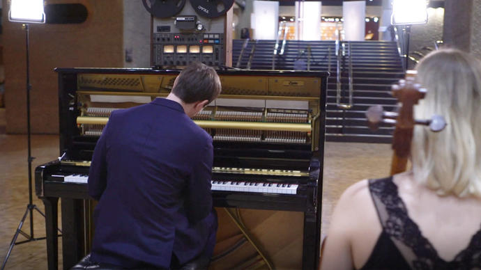 photo of erland cooper in front of a piano in the barbican foyer