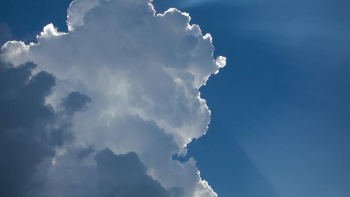 Photo of the sun's rays shining from behind a cloud