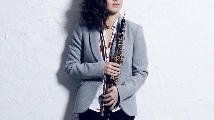 Cristina Gomez Godoy standing in front of a white wall holding her oboe