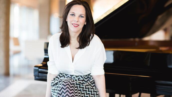 Daria van der Bercken sits on a piano stool, in front of an open grand piano