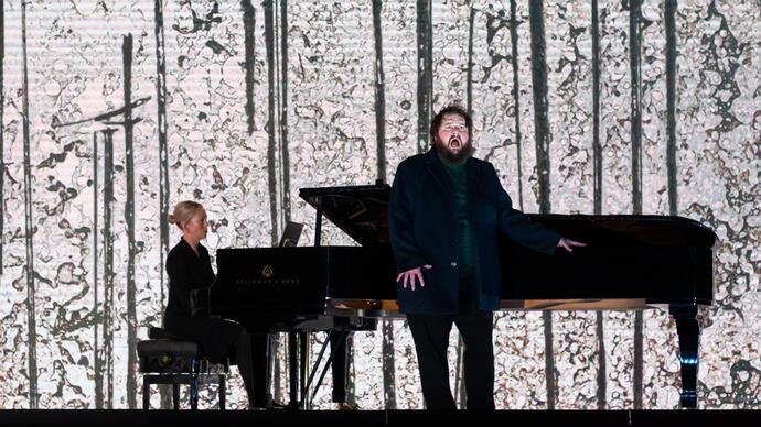 Allan Clayton and Kate Golla performing Winterreise in front of a projection of artwork by Fred Williams