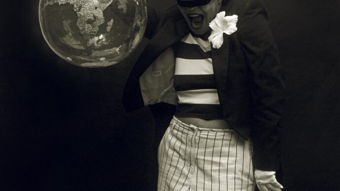 black and white photo of Carie Mae Weems in a top hat, holding up a globe