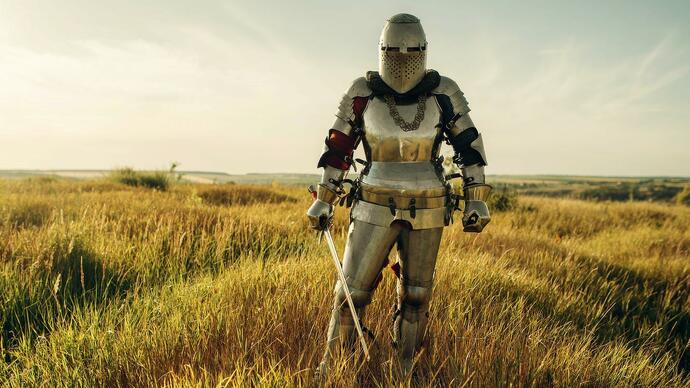 An armoured knight standing in a grassy field holding a sword