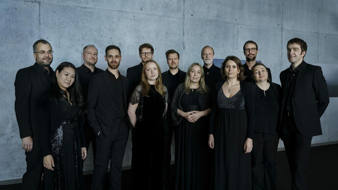 Members from Collegium Vocale Gent dressed in black, standing in front of a concrete wall