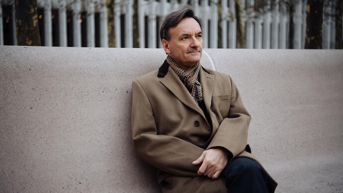 Stephen Hough sitting on a concrete bench