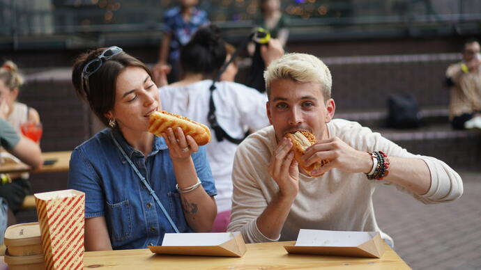 Two influencers munch a hot dog