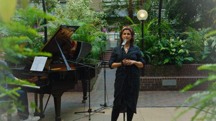 Stephanie J. Block stands behind a microphone next to a baby grand piano in our conservatory.