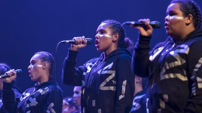 Three singers performing Spinifex Gum on stage, holding microphones