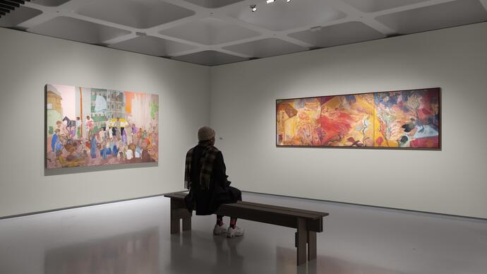 a person sits on a bench in front of two paintings