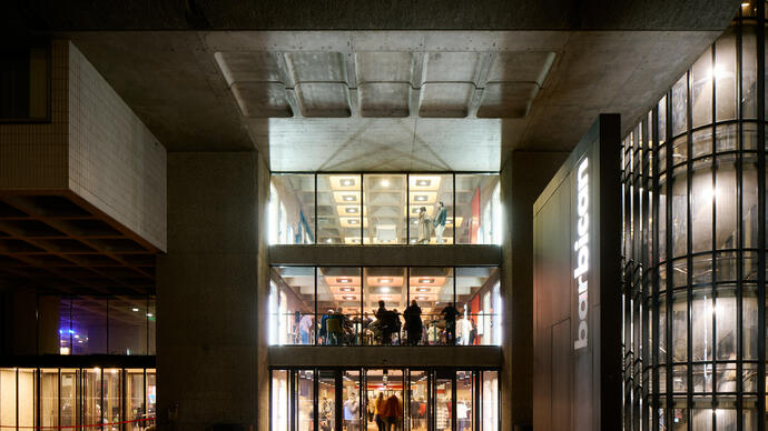 A night time shot of the Barbican looking inside to bright light and people