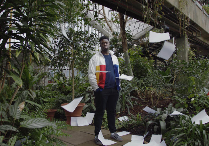 Man standing in conservatory surrounded by paper