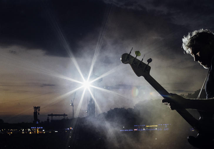 Roger Waters playing the guitar silhouetted against the sky