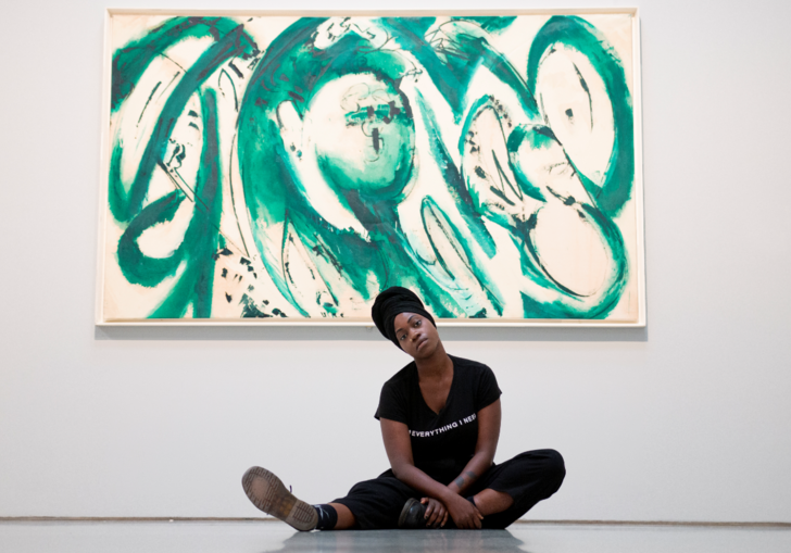 image of young poet anita barton-williams sitting on the floor in front of a green painting by lee krasner