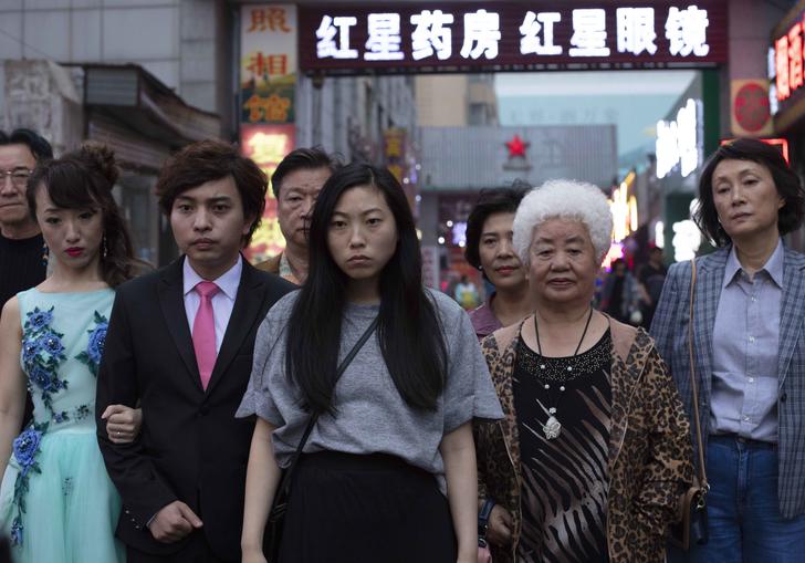 Awkwafina starring in The Farewell standing with her family around her