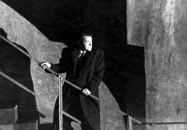 Orson Welles standing on a staircase looking backwards