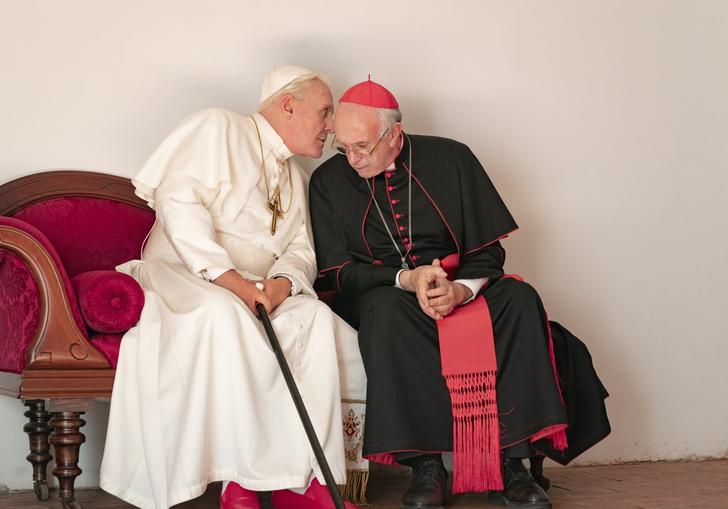 the two popes, Francis and Benedict sit next to each other with one whispering in the other's ear