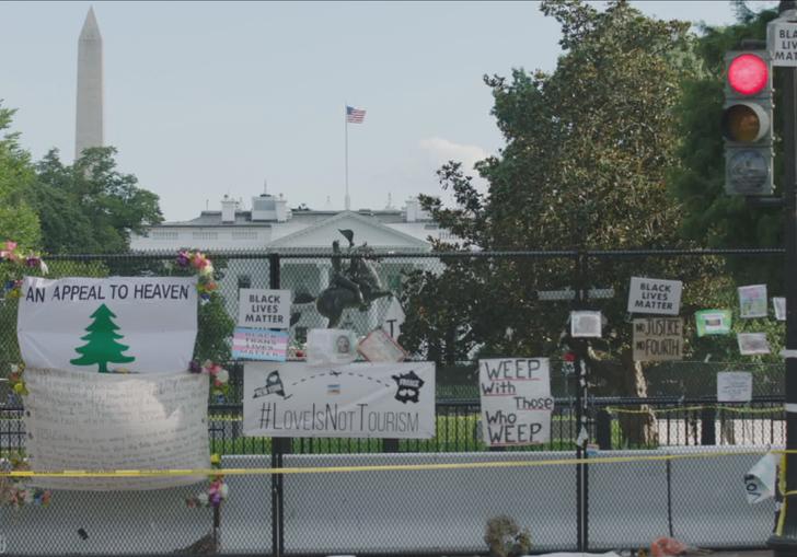 lots of signs tied to a fence in front of Washington DC landmark