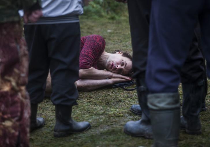 man lying on the ground with people standing around him