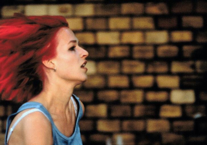 a young woman with red hair runs against a brick wall