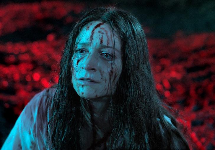 a woman with long brown hair has blood on her head and face