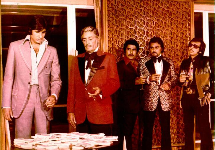 A group of men in 1970s formal wear stand at a table.