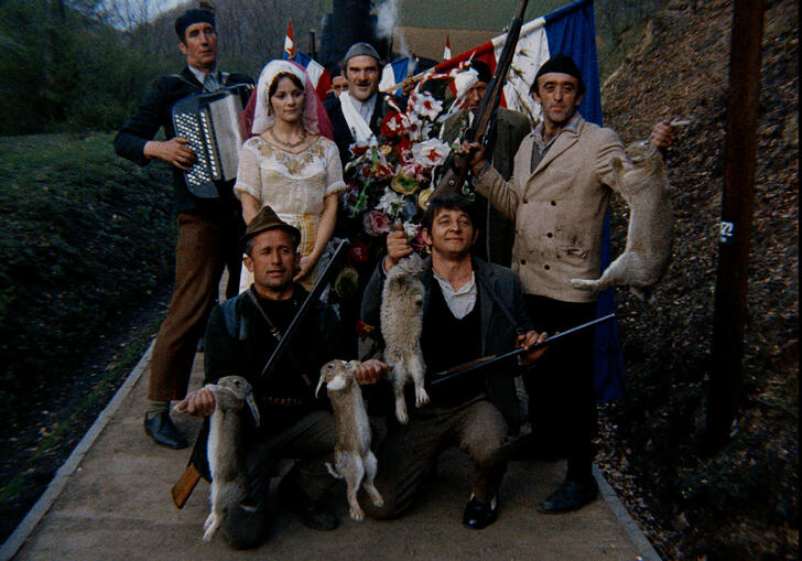 A group of people i =n traditional Yugoslavian dress pose together for a photograph. 