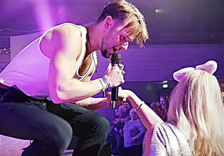 A man bending down to sing to a woman in the audience