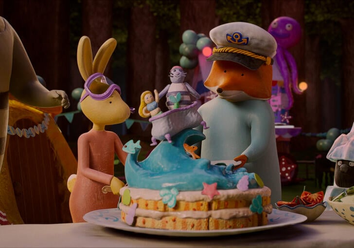 A group of animals stand in a house around a birthday cake. 