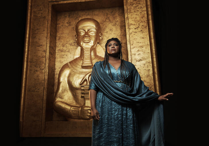 A woman stands besides a statue