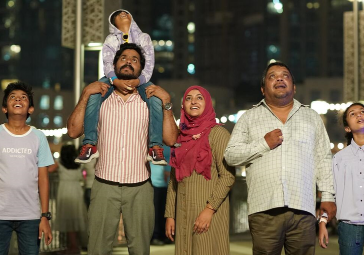 A family stand in a city look forward at the view. 