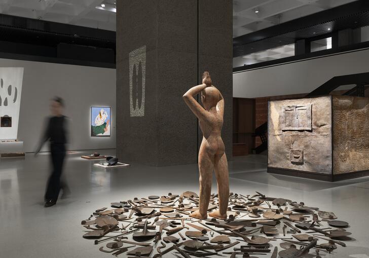 sculpture of a man surrounded by tools, in a gallery