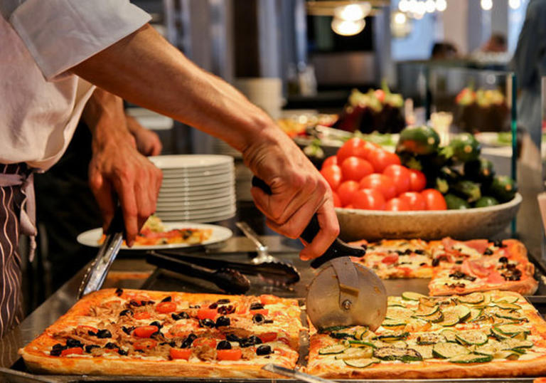 Photo of man cutting a slice of pizza