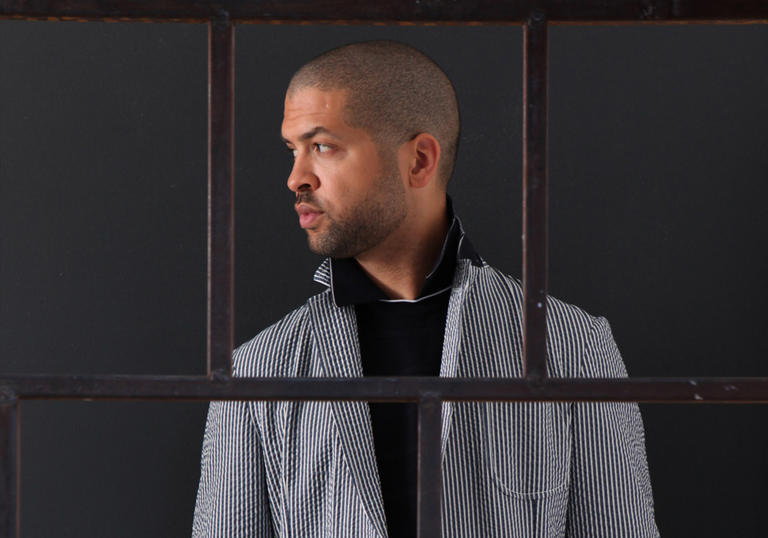 Jason Moran wearing white trousers and stripey blazer looking at something intriguing to his right