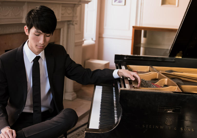 Pianist Eric Lu sits by a piano