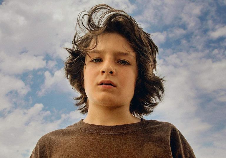 Sunny Suljic looking to camera in front of a cloudy blue sky.