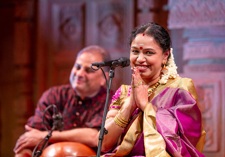 Sudha Ragunathan on stage, her hands are together in a demonstration of thanks