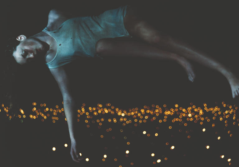 A woman lying horizontally above a city of lights