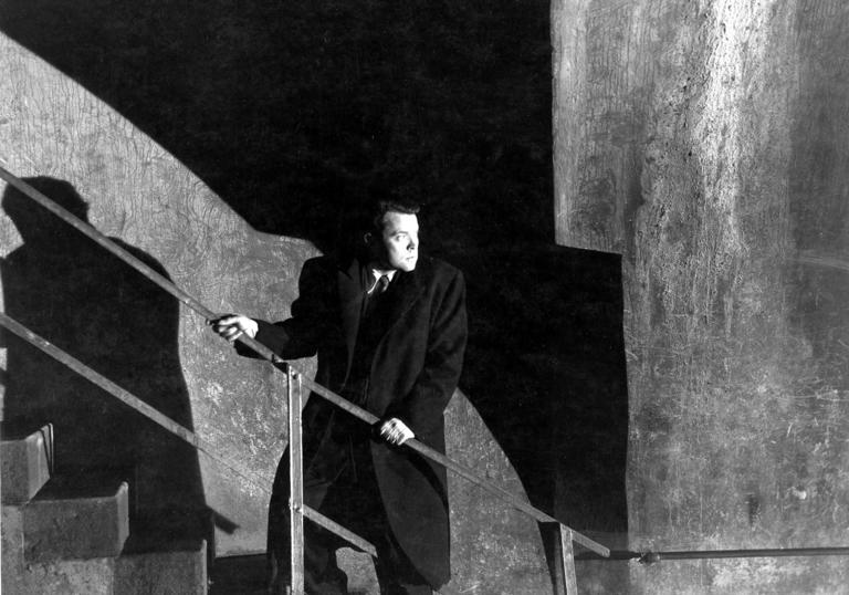 Orson Welles standing on a staircase looking backwards