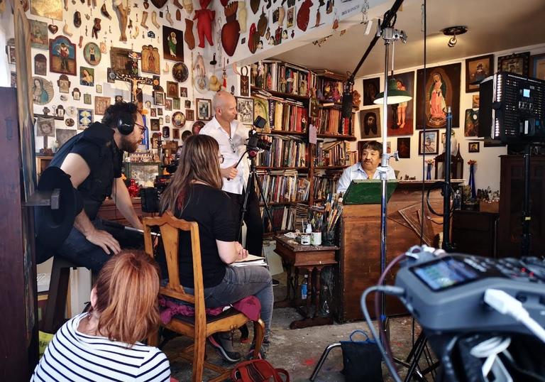 a camera crew in a room filming a man at a piano