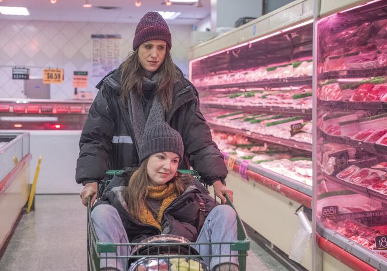 two women in a supermarket together, one pushing a trolley the other in the trolley