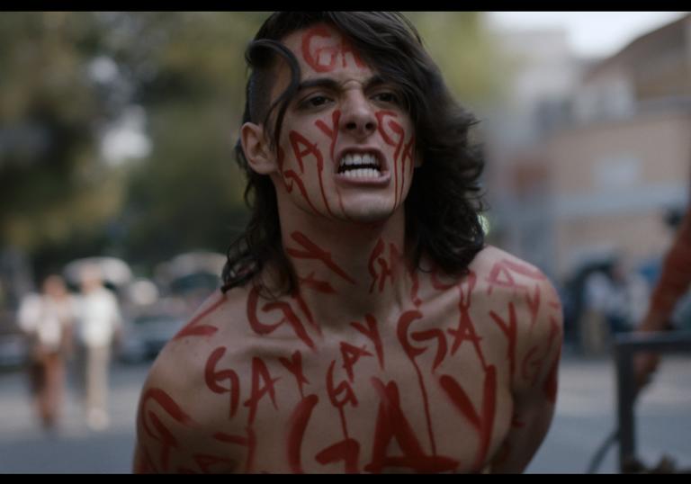 a man covered in red writing protests on the street