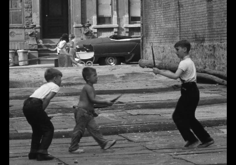 three boys play with sticks in the middle of the city