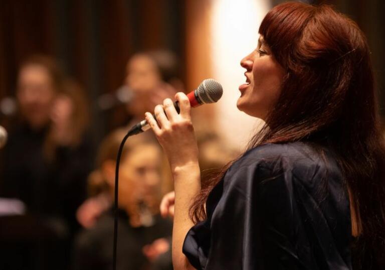 Image of a female jazz singer in profile, singing into microphone
