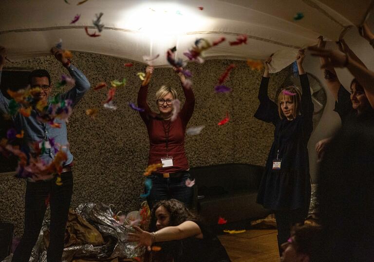 group of people standing around with hands in the air and feathers thrown in room