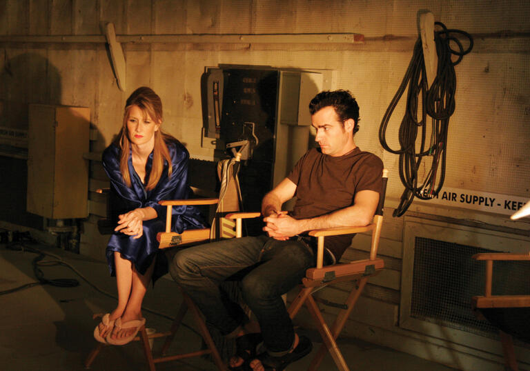 An actor and director sit on a dark set in a still from Inland Empire
