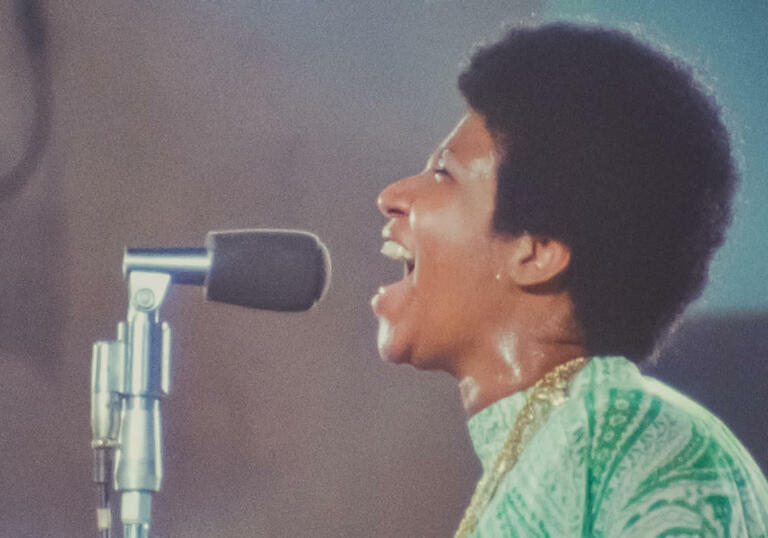 Aretha Franklin sings into a mic 