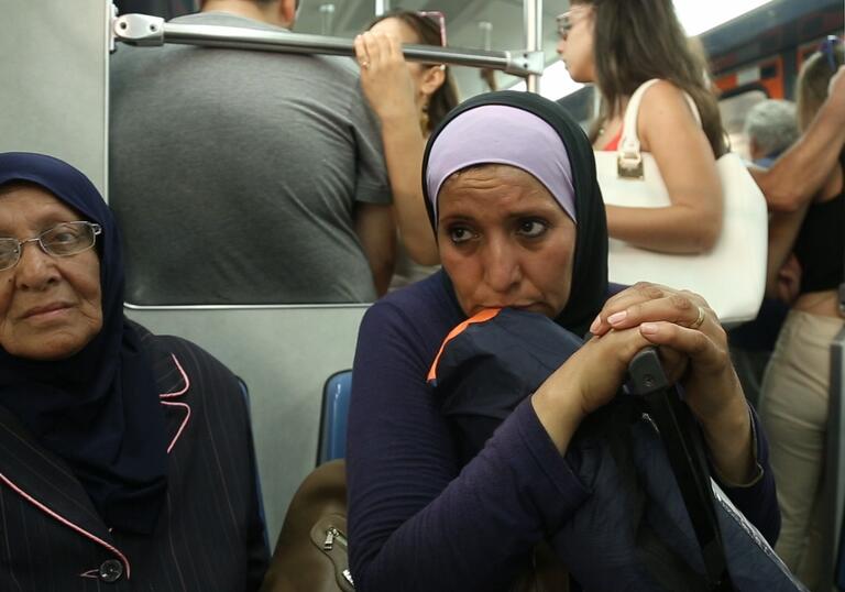 A woman sits on a train in a still from the film.