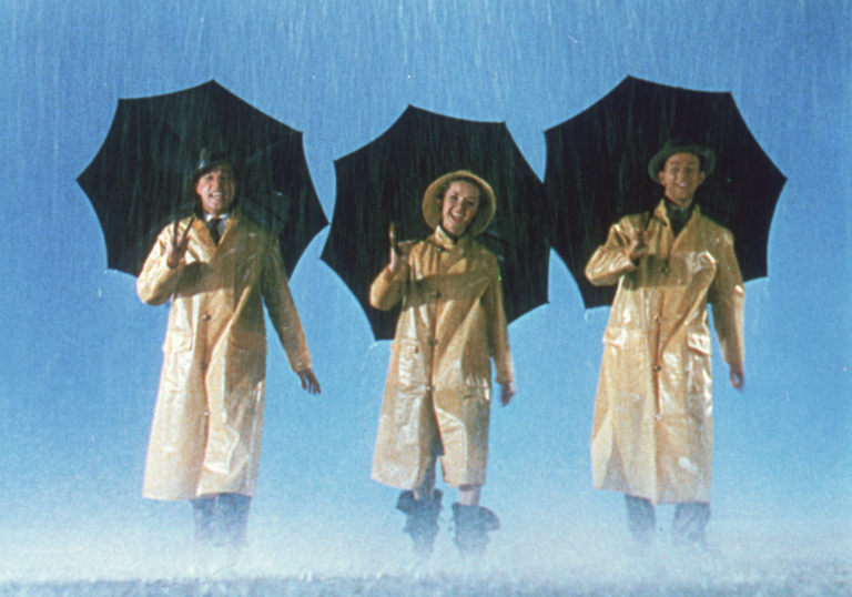 People grinning under umbrellas as the rain falls